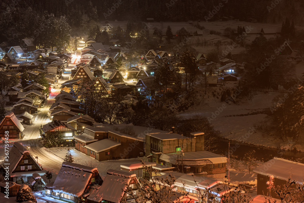 Traditional Japanese village amid trees and snow on misty winter night