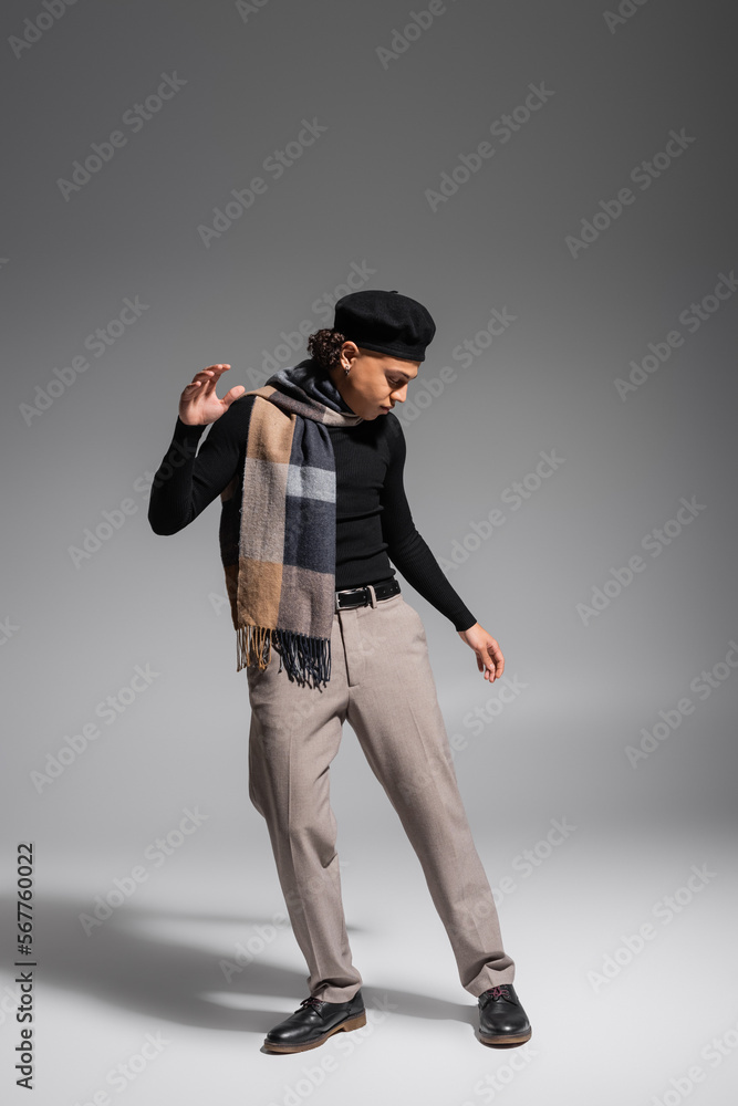 full length of stylish african american man in black sweater and plaid scarf with beret posing on grey background full length of stylish african american man in black sweater and plaid scarf with beret posing on grey background
