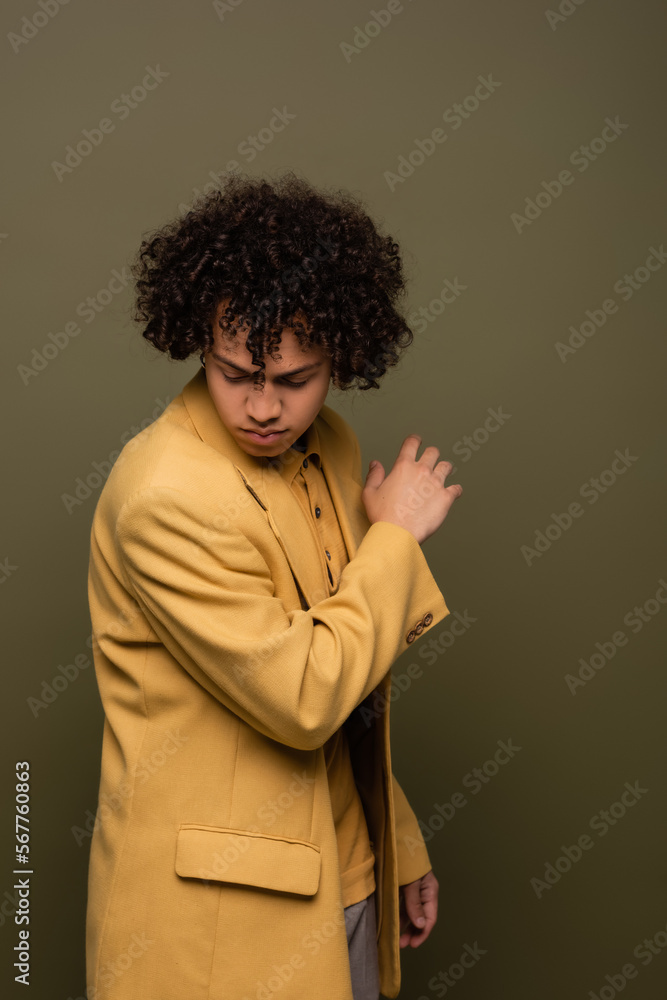 young african american man in stylish yellow jacket posing on grey green background