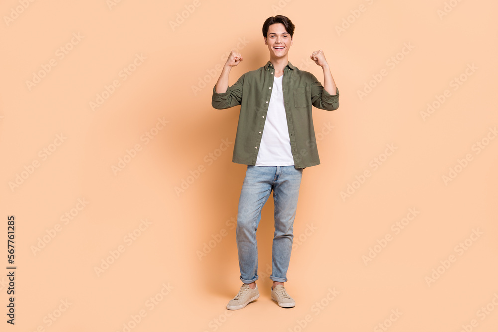 Full body size cadre of youngster guy wearing stylish casual outfit raise fists up celebrate final season sale isolated on beige color background Full body size cadre of youngster guy wearing stylish casual outfit raise fists up celebrate final season sale isolated on beige color background