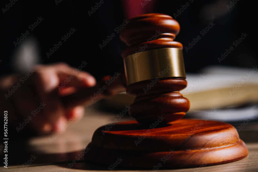 Justice and law concept.Male judge in a courtroom with the gavel, working with, computer and docking keyboard, eyeglasses, on table in morning light Justice and law concept.Male judge in a courtroom with the gavel, working with, computer and docking keyboard, eyeglasses, on table in morning light