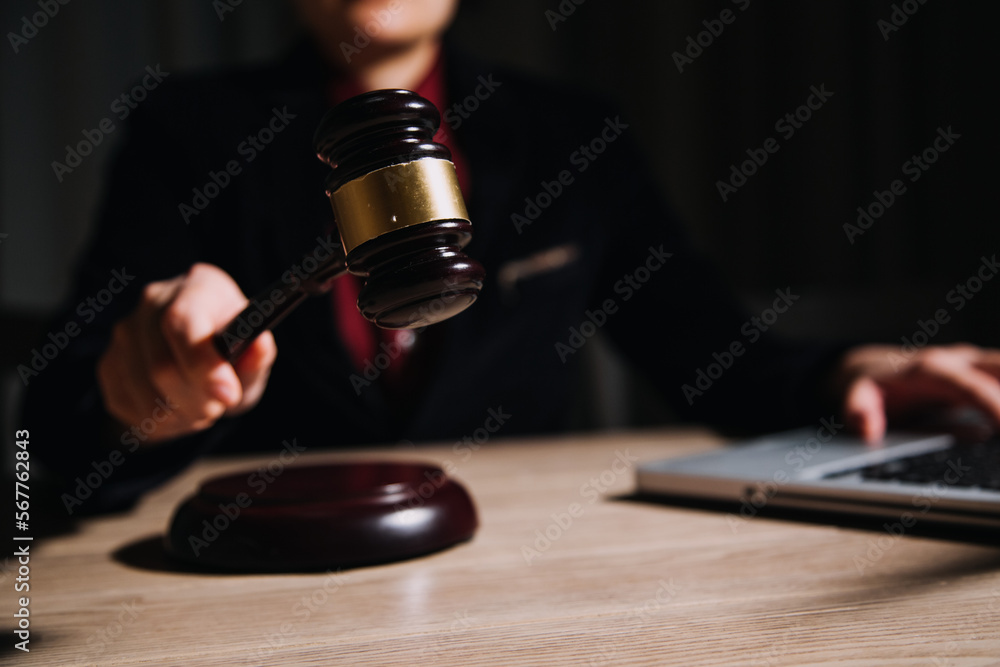 Justice and law concept.Male judge in a courtroom with the gavel, working with, computer and docking keyboard, eyeglasses, on table in morning light Justice and law concept.Male judge in a courtroom with the gavel, working with, computer and docking keyboard, eyeglasses, on table in morning light
