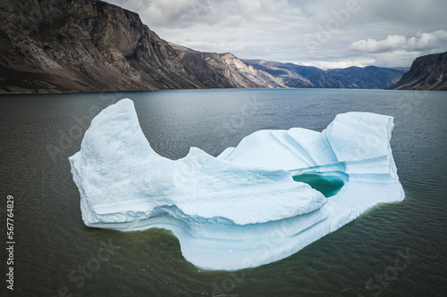Big blue iceberg reflecting in water floats in the sea by Broughton Island, Nunavut, Canada. auyuittuq national park