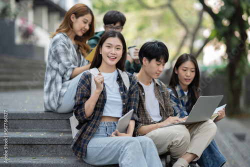 Potrait of young Asian college students working on group project while sitting on staircase of college campus. © Parichat
