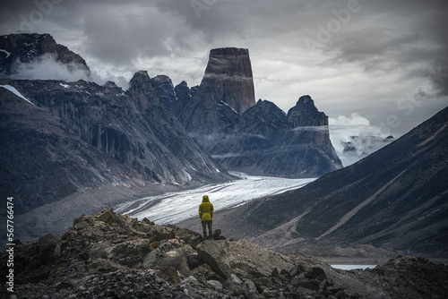 A man standing on a stone cliff in Akshayuk Pass, Nunnavut, Canada. Foggy mountains, cloudy morning in Buffin Island. photo