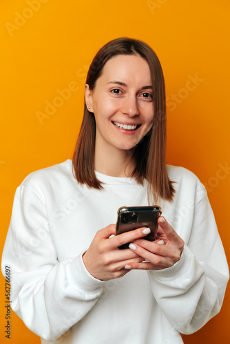 Vertical portrait of a wide smiling woman holding and enjoying her new phone.