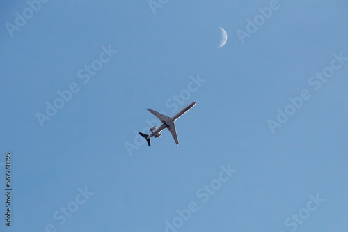 passenger plane flies high in the sky. next to it is the moon