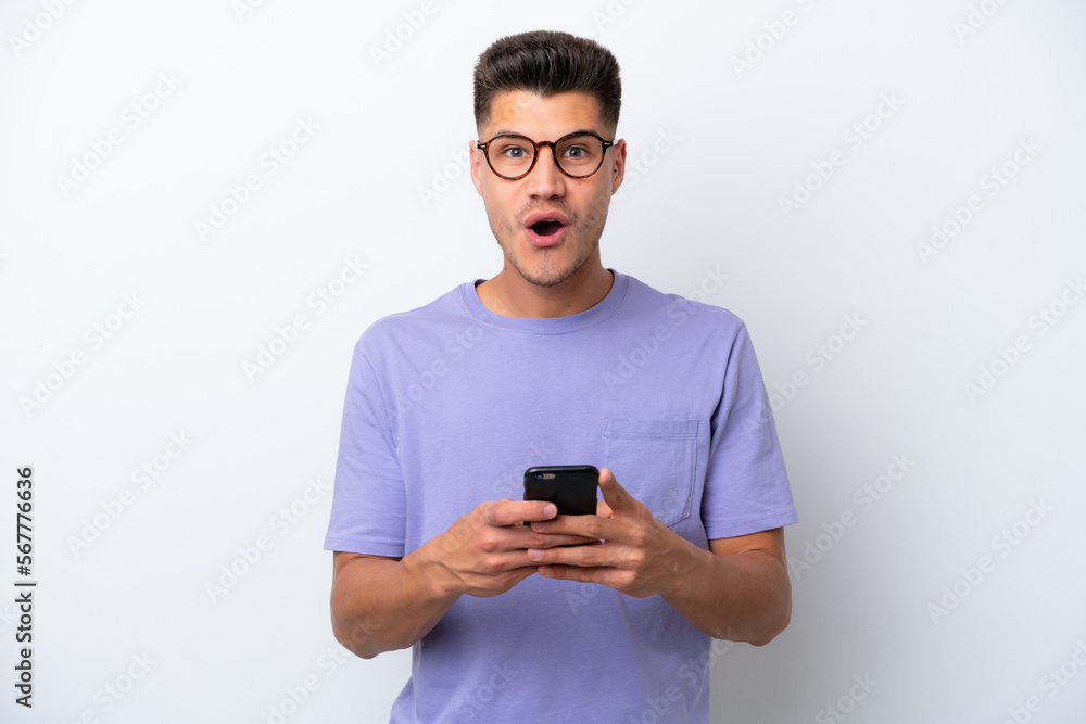 Young caucasian man isolated on white background surprised and sending a message Young caucasian man isolated on white background surprised and sending a message