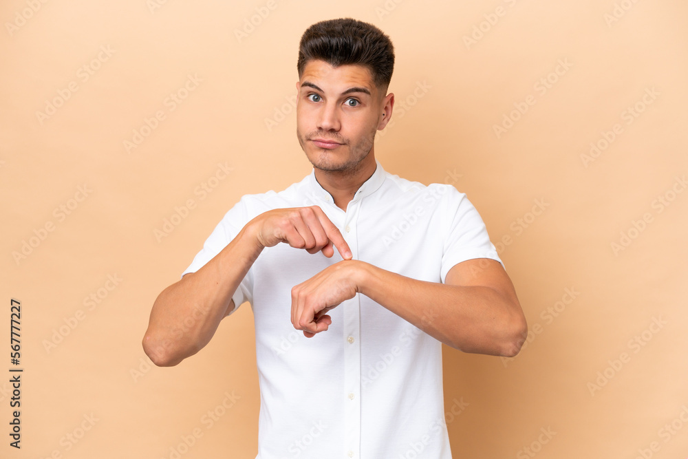 Young caucasian man isolated on beige background making the gesture of being late Young caucasian man isolated on beige background making the gesture of being late
