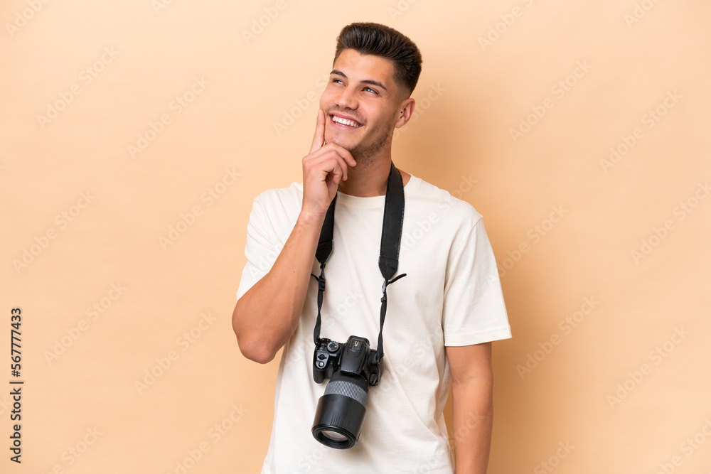 Young photographer caucasian man isolated on beige background thinking an idea while looking up Young photographer caucasian man isolated on beige background thinking an idea while looking up