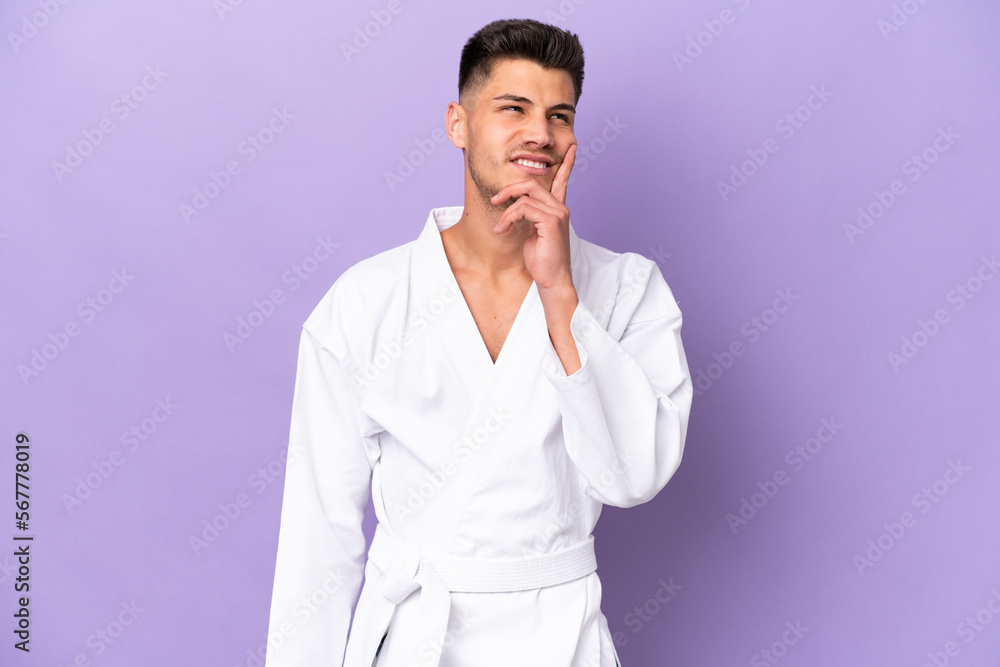 Young caucasian man doing karate isolated on purple background thinking an idea while looking up Young caucasian man doing karate isolated on purple background thinking an idea while looking up