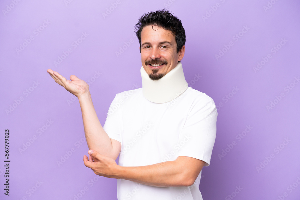 Young caucasian man wearing neck brace isolated on purple background extending hands to the side for inviting to come