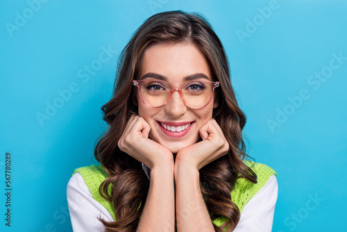 Portrait of adorable cheerful girl arms touch cheeks beaming smile isolated on blue color background