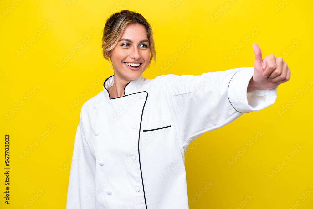 Uruguayan chef woman isolated on yellow background giving a thumbs up gesture Uruguayan chef woman isolated on yellow background giving a thumbs up gesture