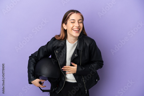 Young caucasian woman holding a motorcycle helmet isolated on purple background smiling a lot