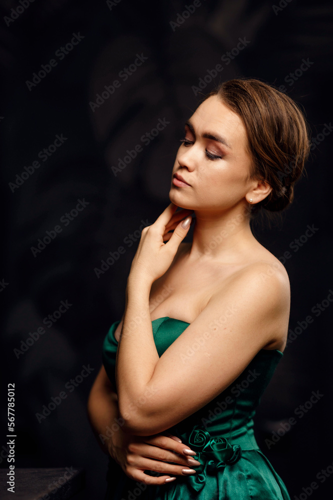A girl in a green dress on a dark background A girl in a green dress on a dark background