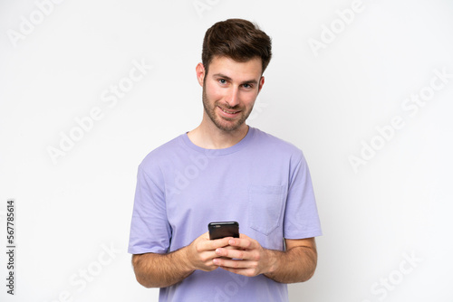 Young caucasian man isolated on white background sending a message with the mobile © luismolinero