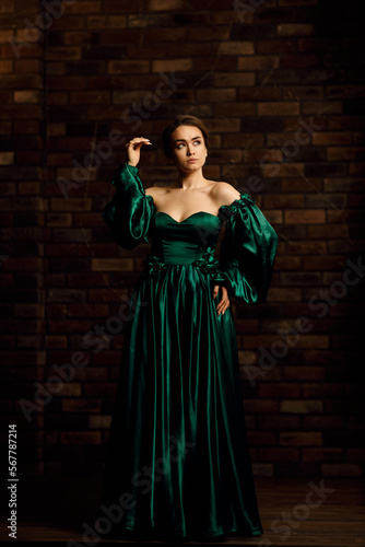 Full-length portraits of a girl in a green dress against a brown brick wall