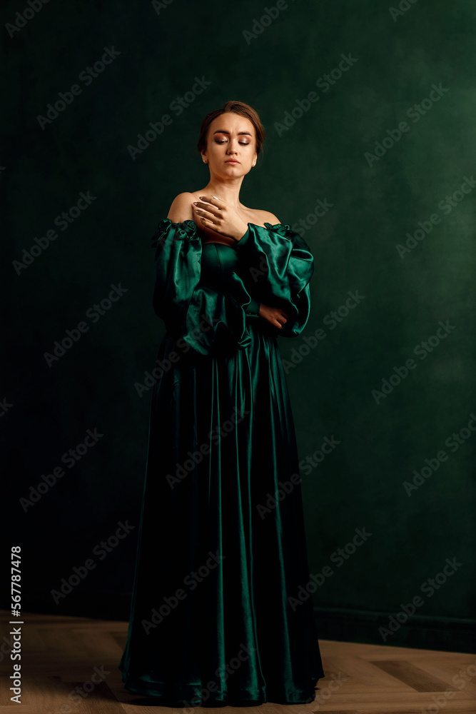 a girl in a green dress standing against a green wall a girl in a green dress standing against a green wall