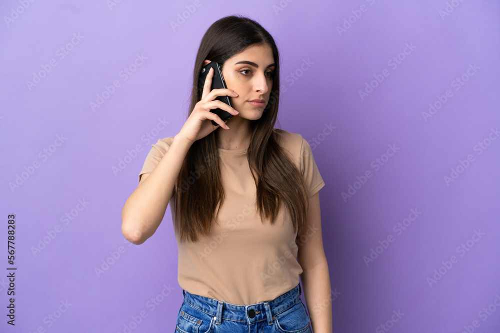 Young caucasian woman using mobile phone isolated on purple background looking to the side Young caucasian woman using mobile phone isolated on purple background looking to the side
