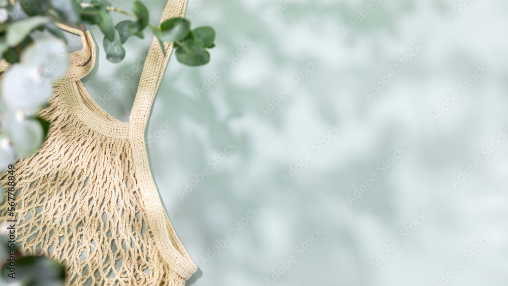 Eco friendly shopping concept. Environment, sustainable composition with natural textile bag on blue background with green leaves and shadows. Flat lay, copy space Eco friendly shopping concept. Environment, sustainable composition with natural textile bag on blue background with green leaves and shadows. Flat lay, copy space