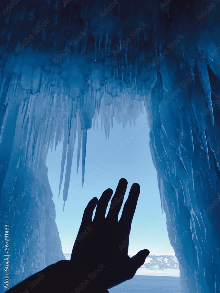 Silhouette of an outstretched hand reaching for icicles, Lake Baikal