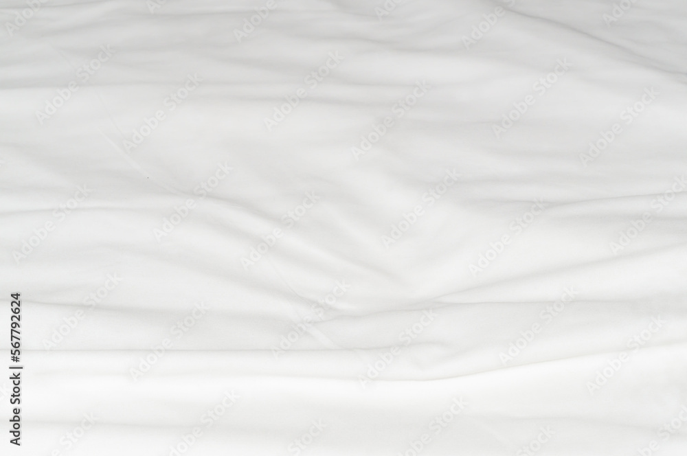 White crumpled or wrinkled bedding sheet or blanket with pattern after guest's use taken in hotel or resort room with copy space. Untidy blanket background texture