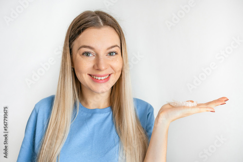 Young european doctor woman on white background holding an invisible aligner. Dental healthcare and confidence concept.
