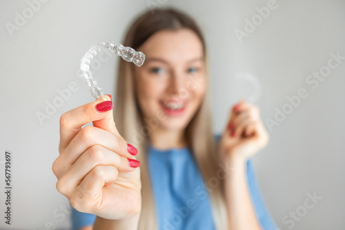 Female hand holding Invisalign, the invisible braces aligner at face woman background. Correction of teeth concept photo