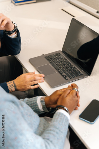 A close up photo of two workers working on a same lap top photo