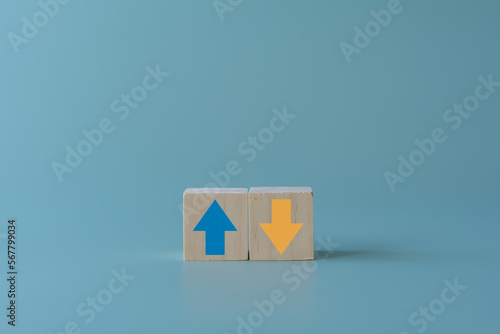Wooden block with up and down arrow concept of differentiation or Opposite direction. Blue arrow up for positive but yellow arrow down for negative. Business trend concept using wooden blocks.