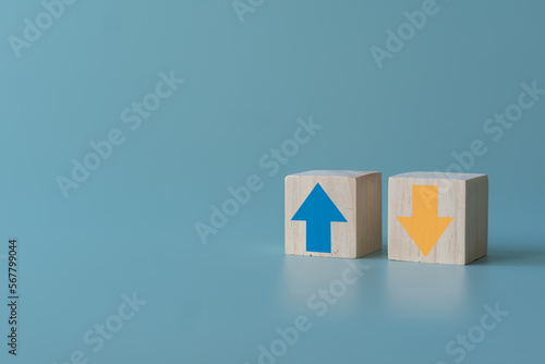 Wooden block with up and down arrow concept of differentiation or Opposite direction. Blue arrow up for positive but yellow arrow down for negative. Business trend concept using wooden blocks.