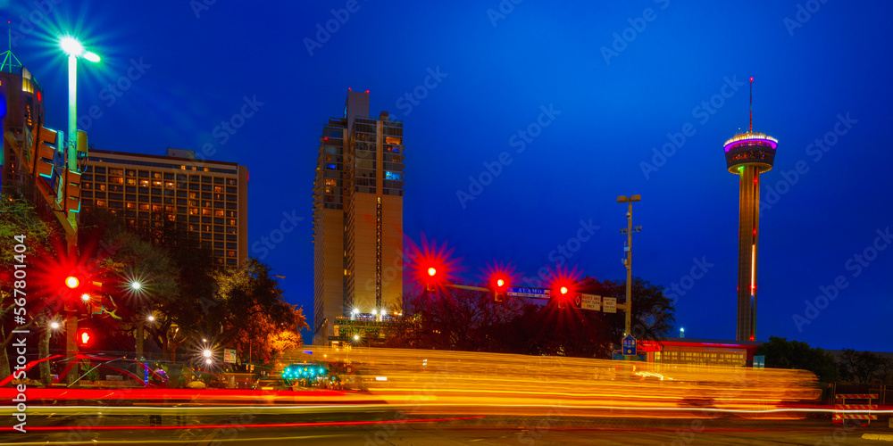 San Antonio Texas night street landscape at moon rise with car light trails, skyline buildings, and the Tower of Americas in winter