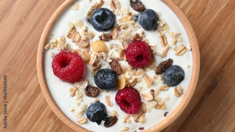 Yogurt with berries and muesli for breakfast in bowl on blue background. Top view Yogurt with berries and muesli for breakfast in bowl on blue background. Top view