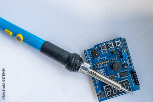 on a white background lies an electronic board with a soldering iron. Tool for soldering electronics.