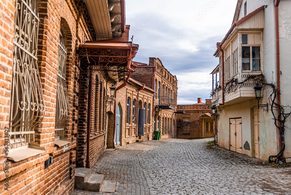 Fototapeta premium Cozy old street with stone pavement in the town of Signagi in Kakheti region, Georgia. Georgian touristic town of love. Tile roof.