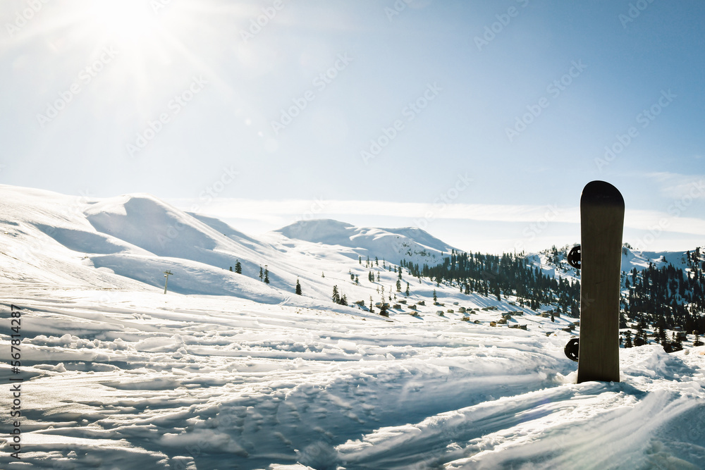 Obraz premium Black base of snowboard in a snow with white mountains in the background. Concept of new ski season.