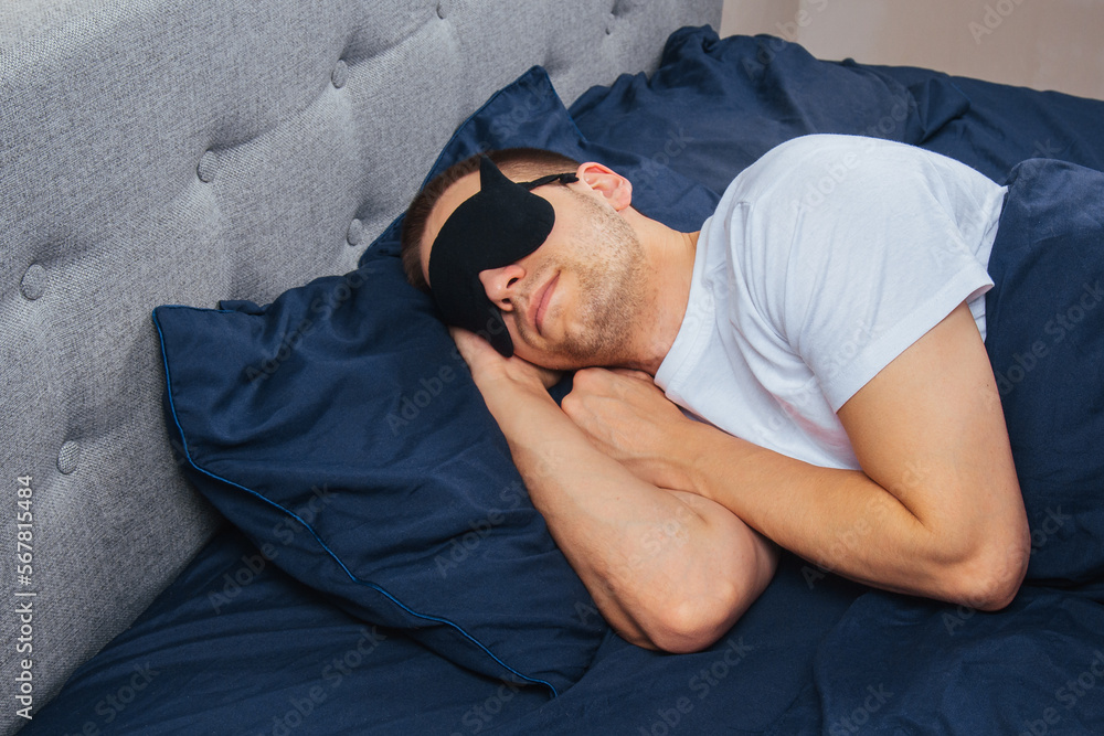 Top view of a young man wearing a sleep mask resting in his bedroom. Relaxation, rest after work. Top view of a young man wearing a sleep mask resting in his bedroom. Relaxation, rest after work.