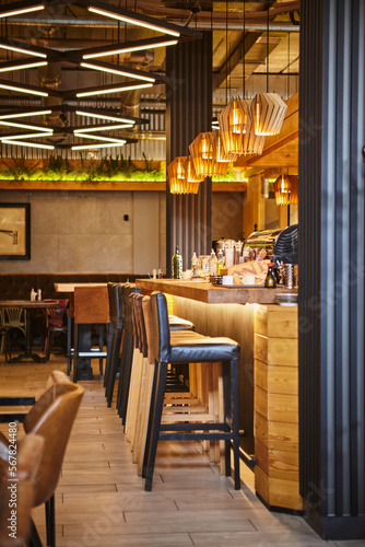 Interior of modern restaurant. Design in loft style, modern dining place and bar counter. Pub culture and drinking. Various alcohol bottles, back light.