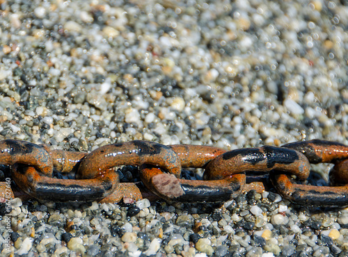 rusty metal anchor chain on coast pebble stones 