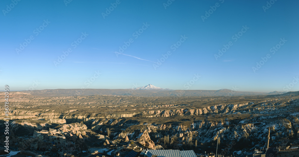 Panoramic view of Cappaadocia area, Ürgüp, Nevşehir, Turkey. Erciyes Mountain at the horizon, one of the highest mountain in Turkey. Clear blue sky.