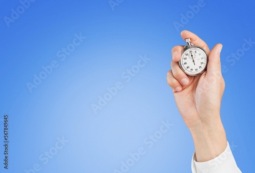 Classic clock in a human's hand on color background