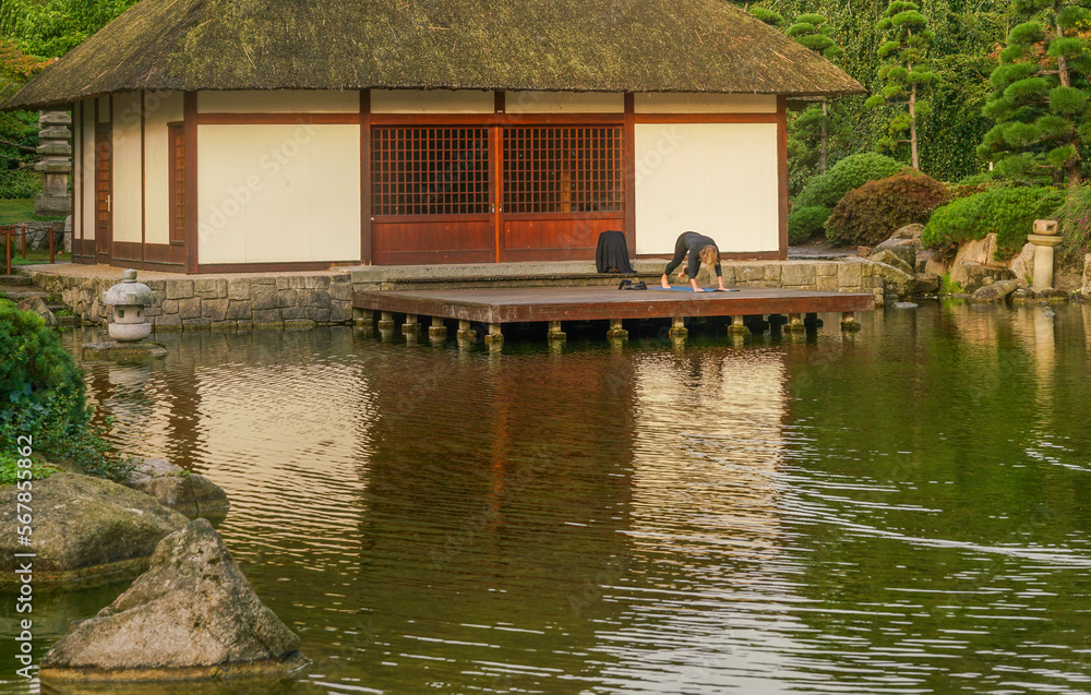A woman practices yoga next to a teahouse in a Japanese garden in Hamburg