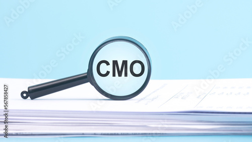 magnifying glass with CMO - Chief Marketing Officer, inscription on a blue background. photo