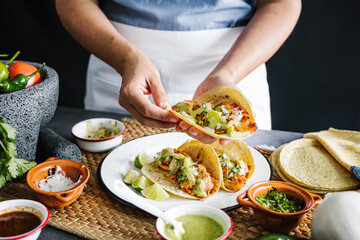 Mexican woman hands preparing tacos al pastor and eating mexican food in Mexico Latin America