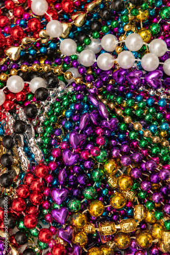 Many colorful mardi gras beads in a pile background