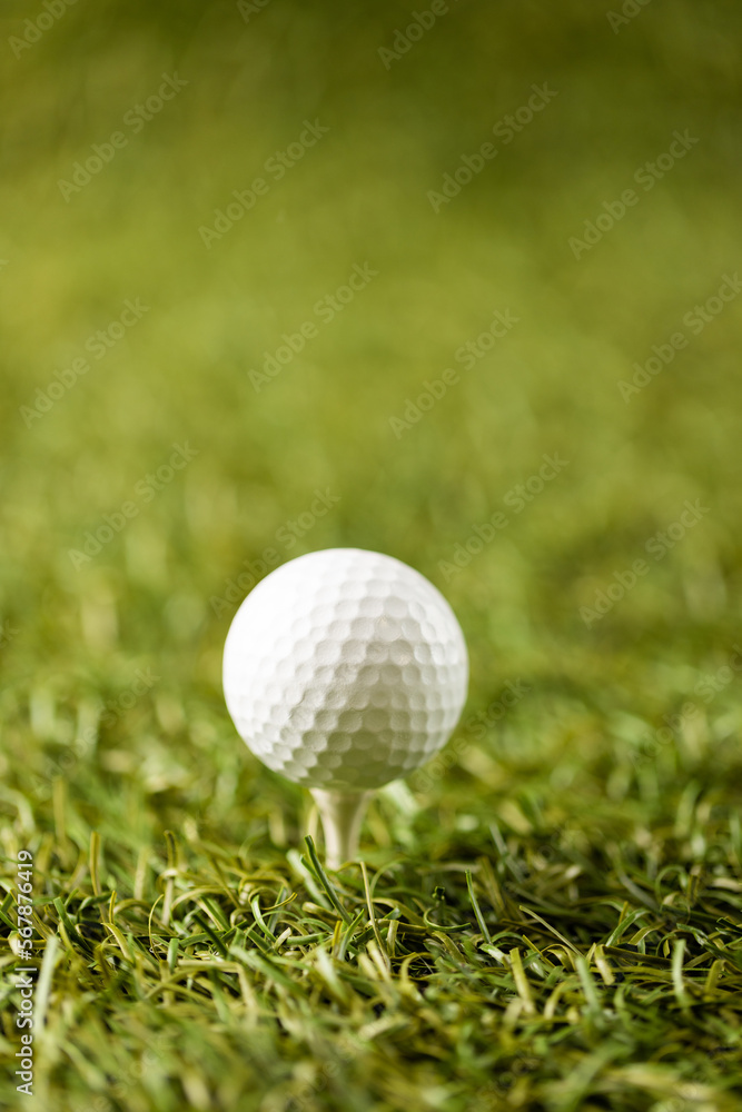 Close up of white golf ball on golf tee on grass with copy space Close up of white golf ball on golf tee on grass with copy space