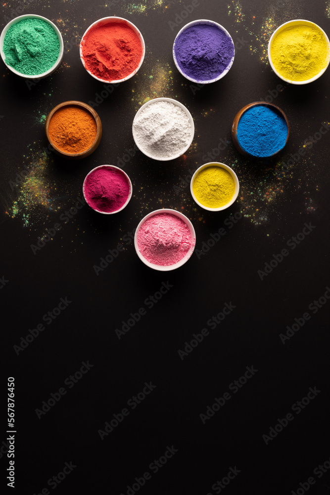 Close up of multi coloured powder in bowls with copy space on black background Close up of multi coloured powder in bowls with copy space on black background