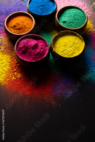 Close up of multi coloured powder in bowls and copy space on black background