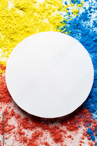 Close up of multi coloured powder and white circle with copy space on white background